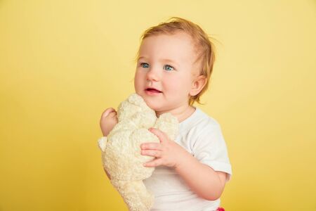 Caucasian little girl, children isolated on yellow studio background. Portrait of cute and adorable...