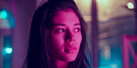 Cinematic close up portrait of stylish woman in neon lighted interior. Toned like cinema effects in...