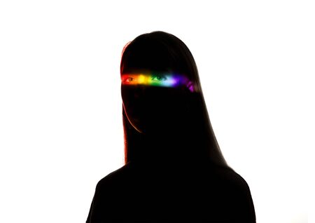 Proud. Dramatic portrait of a girl in the dark on white studio background with rainbow colored line....
