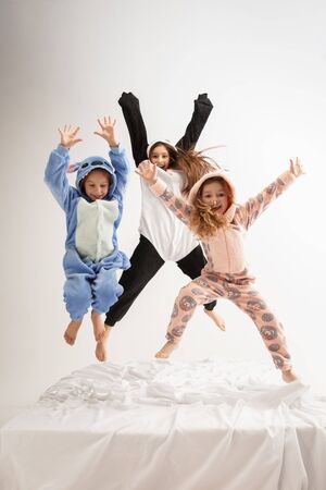 Children in soft warm pajamas colored bright playing at home. Little girls having fun, party, laughting, jumping together, look stylish and happy. Concept of childhood, leisure activity, happiness.の写真素材