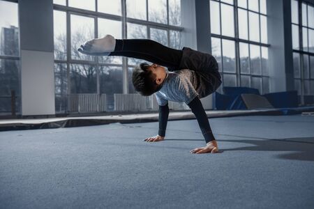 Little male gymnast training in gym, flexible and active. Caucasian fit little boy, athlete in...