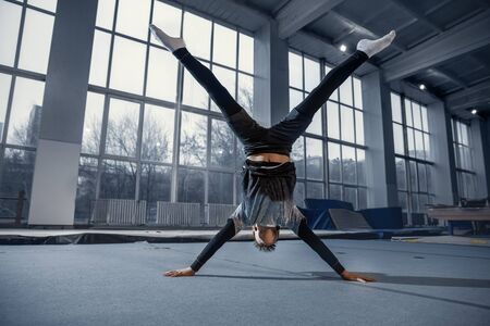 Little male gymnast training in gym, flexible and active. Caucasian fit little boy, athlete in sportswear practicing in exercises for strength, balance. Movement, action, motion, dynamic concept.の写真素材