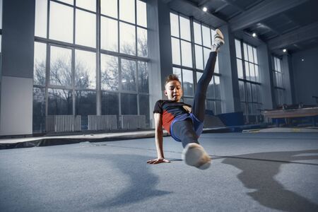 Little male gymnast training in gym, flexible and active. Caucasian fit little boy, athlete in...