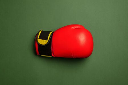 Bright red and yellow boxing glove. Professional sport equipment isolated on green studio...