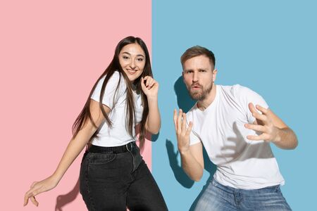 Crazy. Dancing, moving, having fun. Young and happy man and woman in casual clothes on pink, blue...