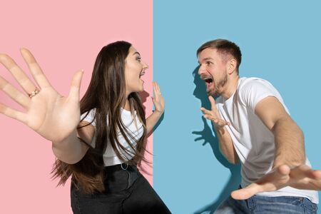 Crazy. Dancing, moving, having fun. Young and happy man and woman in casual clothes on pink, blue bicolored background. Concept of human emotions, facial expession, relations, ad. Beautiful couple.の写真素材