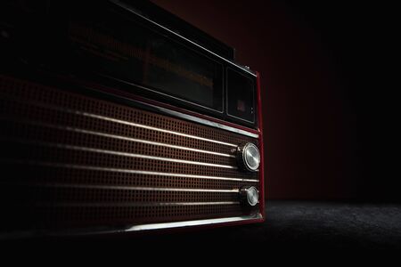 Red radio on dark background. Close up of old retro things shooted with vintage style colors and toned. Flyer for your ad. Concept of retro style, history return, fashioned things, hobby, memories.の写真素材