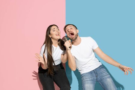 Vibes. Dancing, singing, having fun. Young and happy man and woman in casual clothes on pink, blue bicolored background. Concept of human emotions, facial expession, relations, ad. Beautiful couple.の写真素材