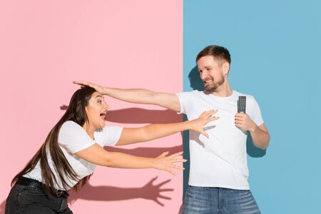 My choice. Fighting for TV channel remote. Young man and woman in casual clothes on pink, blue...