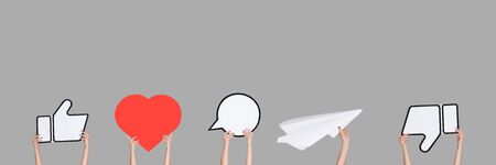 Hands holding the signs of social media on grey background, flyer. Copyspace for your text or image, advertising. Showing meaning, gadgets, modern technologies, comments, message, interactions.の写真素材