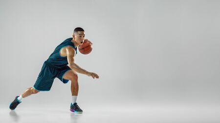 Young basketball player of team wearing sportwear training, practicing in action, motion in run isolated on white background. Concept of sport, movement, energy and dynamic, healthy lifestyle. Flyer.の写真素材