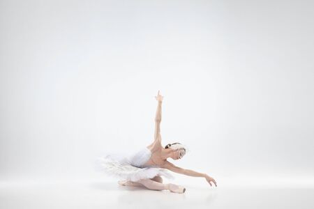 Graceful classic ballerina dancing isolated on white studio background. Woman in tender clothes like a white swan characters. The grace, artist, movement, action and motion concept. Looks weightless.の写真素材