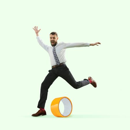 Office worker kicking duct tape like ball on green background. Copyspace for your proposal. Modern design. Contemporary artwork, collage. Concept of sport, office, work, dreams, business, action.の写真素材