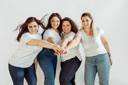 Team. Young caucasian women in casual clothes having fun together. Friends posing on white background and laughting, looks happy, well-kept. Bodypositive, feminism, loving themself, beauty concept.の写真素材
