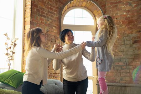 Best emotions. Happy loving family. Grandmother, mother and daughter spending time together. Playing, using tablet, laughting at home. Mothers day, celebration, weekend, holiday and childhood concept.の写真素材