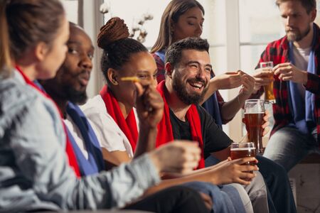 Excited group of people watching football, sport match at home. Multiethnic group of friend, fans...