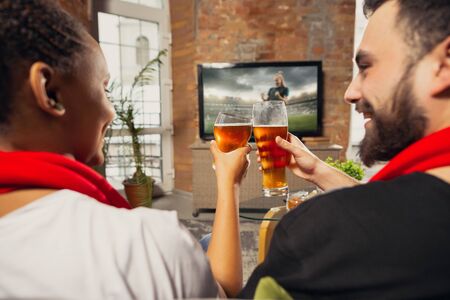 Excited group of people watching football, soccer sport match at home. Multiethnic group of emotional friend, fans cheering for favourite national team, drinking beer. Concept of emotions, support.の写真素材