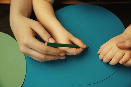 Drawing with colorful pensils. Close up shot of female and kids hands doing different things together. Family, home, education, childhood, charity concept. Mother and son or daughter, wealth.の写真素材