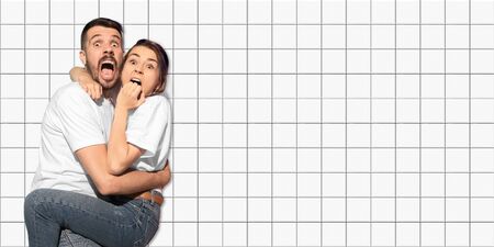 Scared. Caucasian couple portrait on mosaic tiles on the background. Concept of human emotions,...