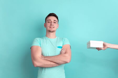 Emotional taking a gift. Caucasian young mans portrait isolated on blue studio background. Beautiful...