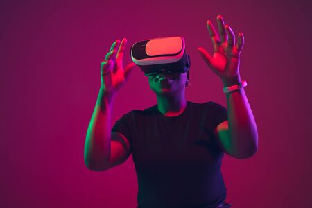 Driving. African-american young womans portrait on purple background. Beautiful female model in VR-headset. Concept of human emotions, facial expression, sales, ad, inclusion, diversity. Copyspace.の写真素材