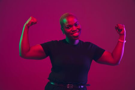 Healthy, strong. African-american young womans portrait on purple background. Beautiful model in black shirt. Concept of emotions, facial expression, sales, ad, inclusion, diversity. Copyspace.の写真素材