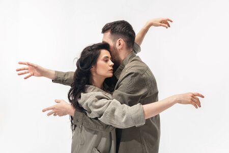 Embracing. Trendy fashionable couple isolated on white studio background. Caucasian woman and man posing in basic minimal stylish clothes. Concept of relations, fashion, beauty, love. Copyspace.の写真素材