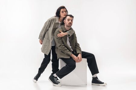 Embracing. Trendy fashionable couple isolated on white studio background. Caucasian woman and man posing in basic minimal stylish clothes. Concept of relations, fashion, beauty, love. Copyspace.の写真素材
