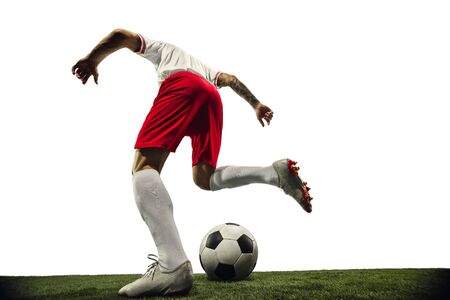 Football or soccer player on white background with grass. Young male sportive model training. Attacking, catching. Concept of sport, competition, winning, action, motion, overcoming. Wide angle.の写真素材