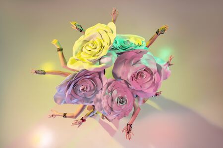Bouquet, top view. Young female dancers with huge floral hats in neon light on gradient background....