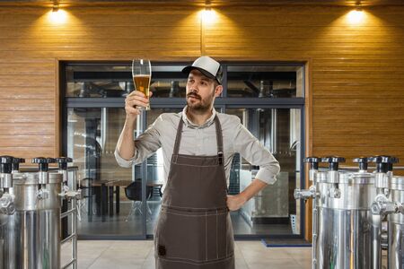 Professional brewer on his own craft alcohol production. Specialist, man wearing in workwear...