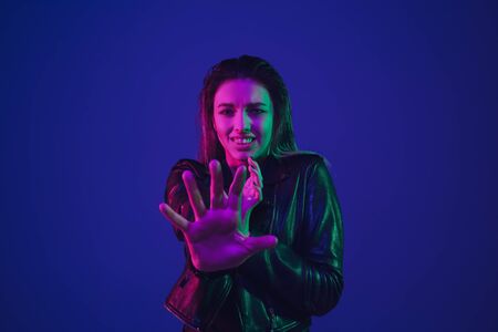 Shocked, scared, rejecting. Caucasian womans portrait isolated on blue studio background in neon...