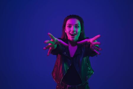 Taking on something. Caucasian womans portrait isolated on blue studio background in neon light....