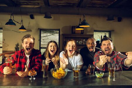 Sport fans cheering at bar, pub and drinking beer while championshipの写真素材