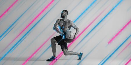 Creative sport and neon lines on grey background, flyer, proposal. Male athlete training with ball...