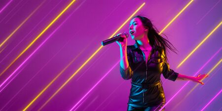 Creative emotions and neon lines on purple background, flyer, proposal. Caucasian young woman,...