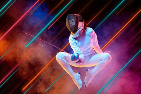 Creative sport and neon lines on dark background, flyer, proposal. Female fencing player training in action and motion. Concept of hobby, healthy lifestyle, youth, action, movement, modern style.の写真素材