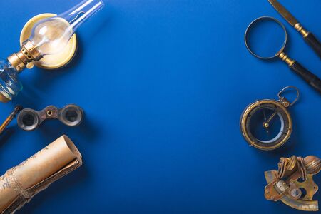 Old fashioned flat lay with retro travel, vacation accessories on blue background. Magnifying glass,...