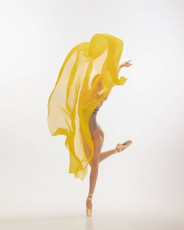 Graceful classic ballerina dancing, posing isolated on white studio background. Bright yellow cloth. The grace, artist, movement, action and motion concept. Looks weightless, flexible. Fashion, style.の写真素材