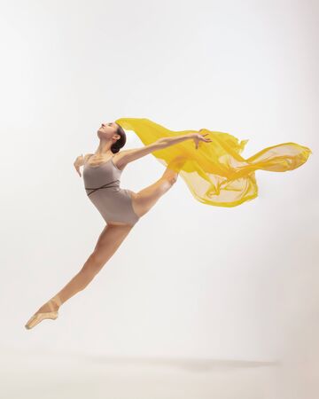 Graceful classic ballerina dancing, posing isolated on white studio background. Bright yellow cloth. The grace, artist, movement, action and motion concept. Looks weightless, flexible. Fashion, style.の写真素材