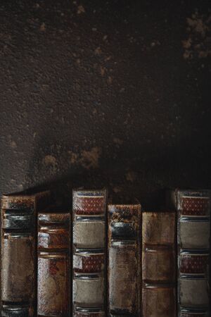 Old fashioned flat lay with stack of antique leather bound books against a dark background. Literature, reading, education concept. Retro, vintage style. Copyspace for your ad. Antique archive.の写真素材
