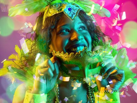 Emotions. Beautiful young woman in carnival, stylish masquerade costume with feathers on gradient...