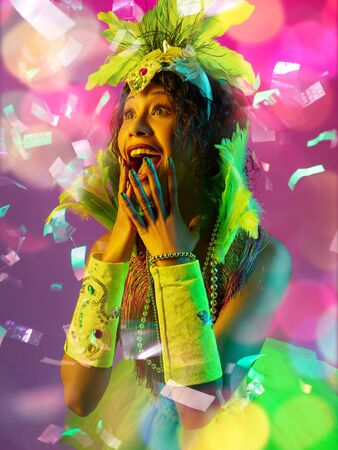 Emotions. Beautiful young woman in carnival, stylish masquerade costume with feathers on gradient...