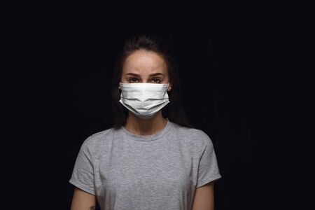 Sad woman in protective mask on black background. Prevention against pneumonia, keep on being on quarantine, staying home. Chinese coronavirus treatment. Healthcare, medicine, isolation concept.の写真素材