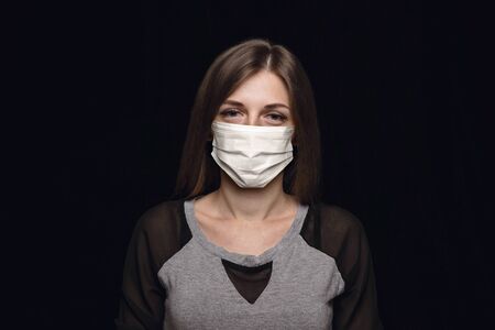 Sad woman in protective mask on black background. Prevention against pneumonia, keep on being on quarantine, staying home. Chinese coronavirus treatment. Healthcare, medicine, isolation concept.の写真素材