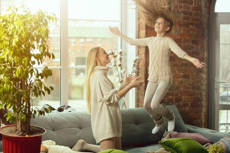 Jumping high. Happy loving family. Mother and daughter spending time together at home. Watching cinema, using laptop, laughting. Mothers day, celebration, weekend, holiday childhood concept.の写真素材
