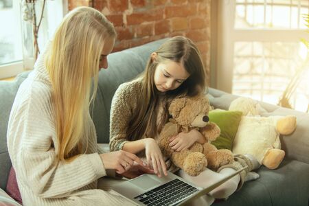 Hearts warming. Happy loving family. Mother and daughter spending time together at home. Watching cinema, using laptop, laughting. Mothers day, celebration, weekend, holiday childhood concept.の写真素材