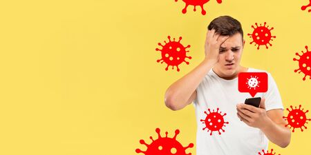 Young man using phone, watching news of coronavirus spreading and worldwide cases, shocked and sad. Flu virus protection, prevention, treatment. Healthcare and medicine. Viruses illustration. Ad.の写真素材