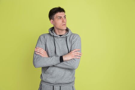 Hands crossed. Caucasian mans portrait isolated on yellow studio background. Freaky male model in...