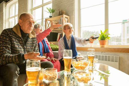 Excited family watching football, sport match at home. Grandparents, parents looking for TV channel with national basketball, football, tennis, soccer, hockey team. Concept of emotions, support.の写真素材